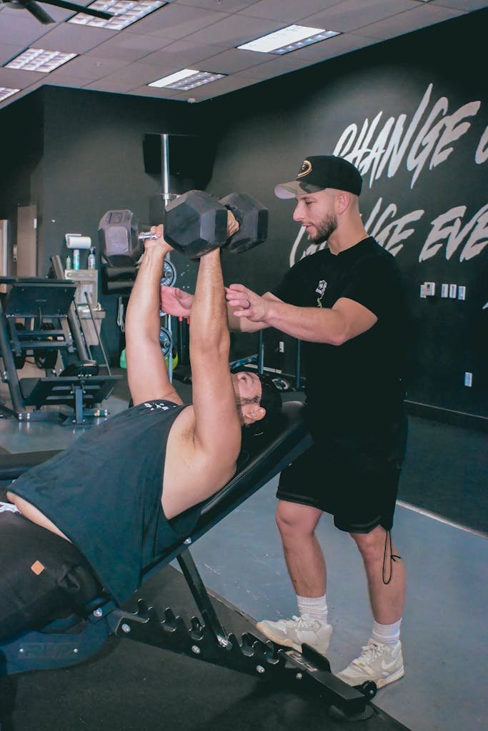A personal trainer guides a client during a dumbbell workout in a Scottsdale, Arizona gym.