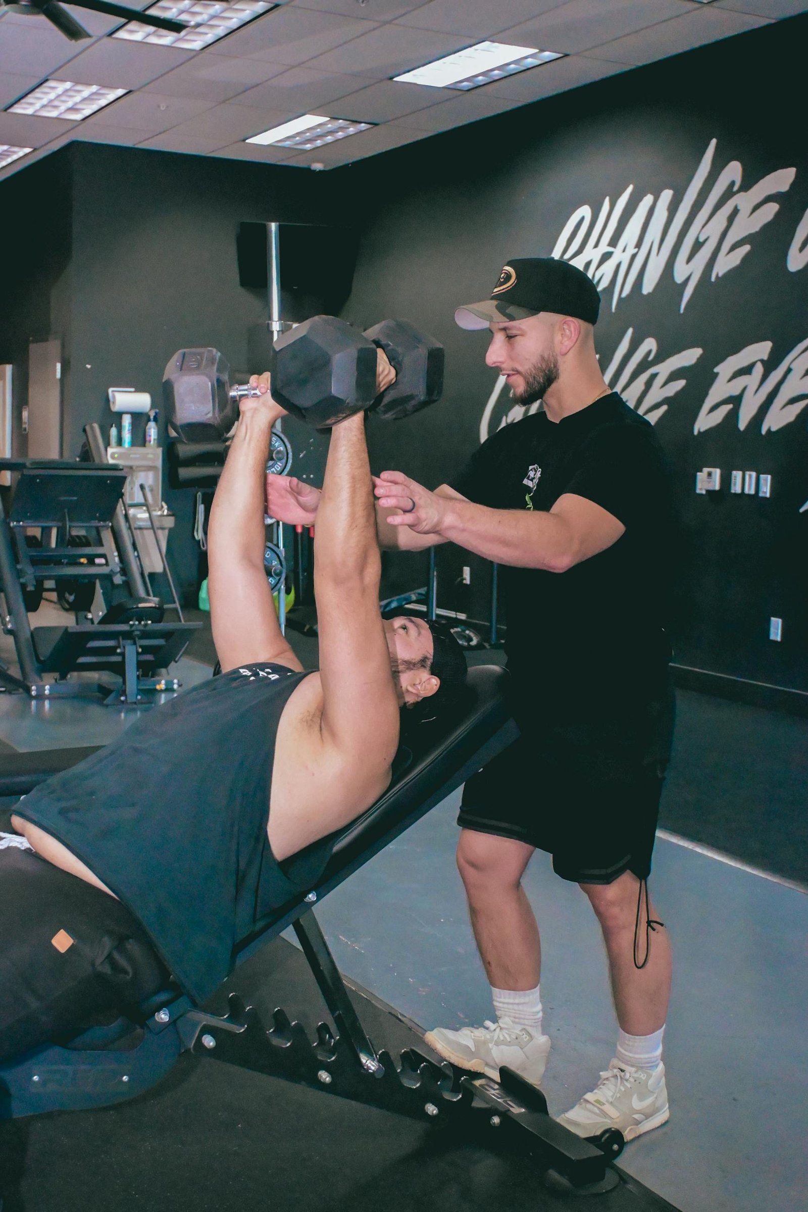 A personal trainer guides a client during a dumbbell workout in a Scottsdale, Arizona gym.